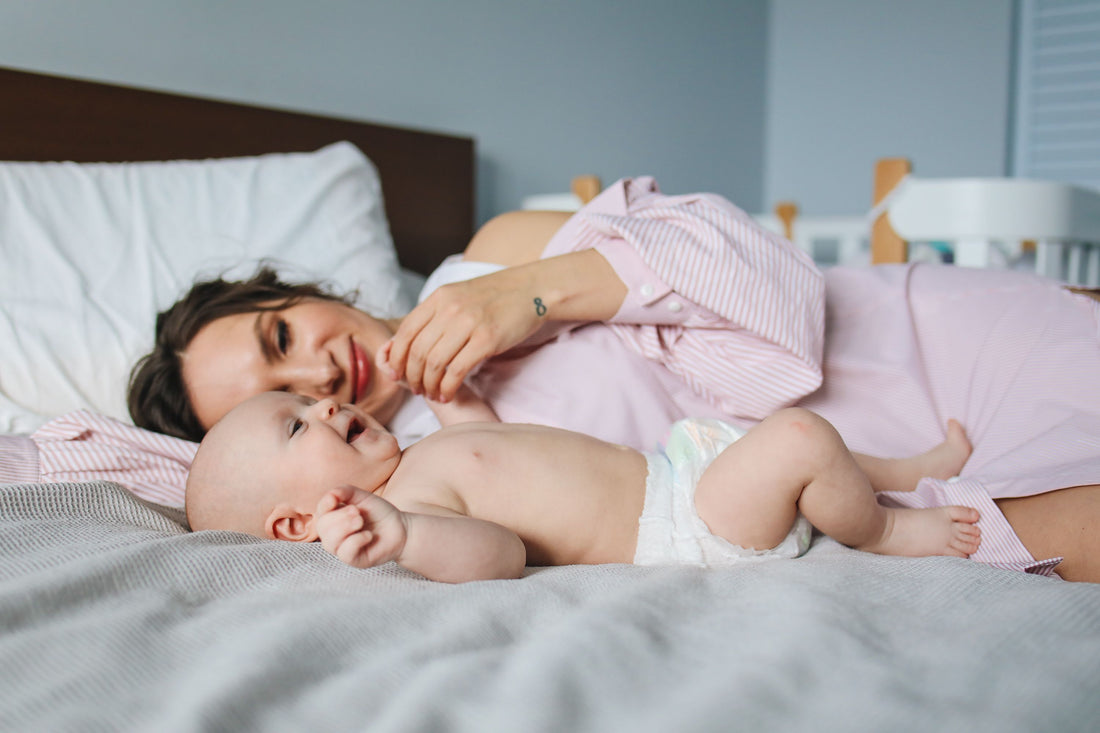 Mamá practicando colecho seguro junto a su bebé recién nacido en la cama
