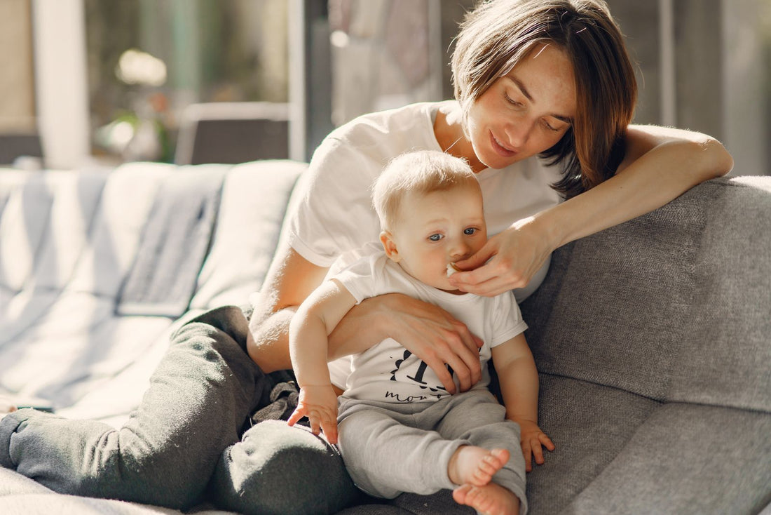 Mamá limpia con cariño la carita de su bebé en casa
