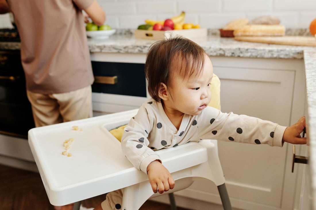 Bebé en silla comedor probando sus primeros alimentos en la cocina